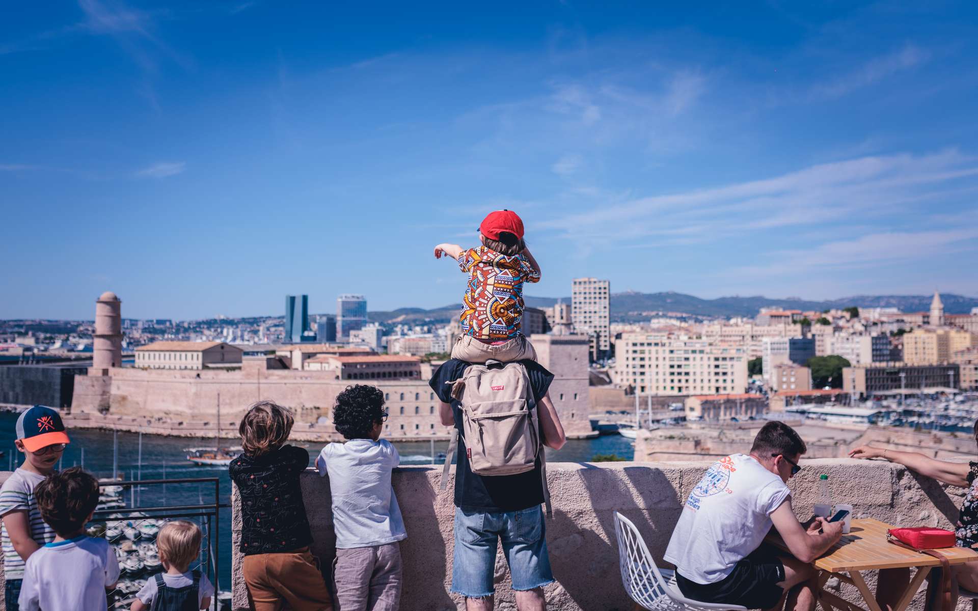 Enfant sur les épaules de son père face à la mer